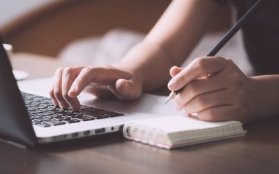 Business situation, female using laptop to get information and memo into paper