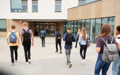 Rear View Of High School Students Walking Into College Building Together